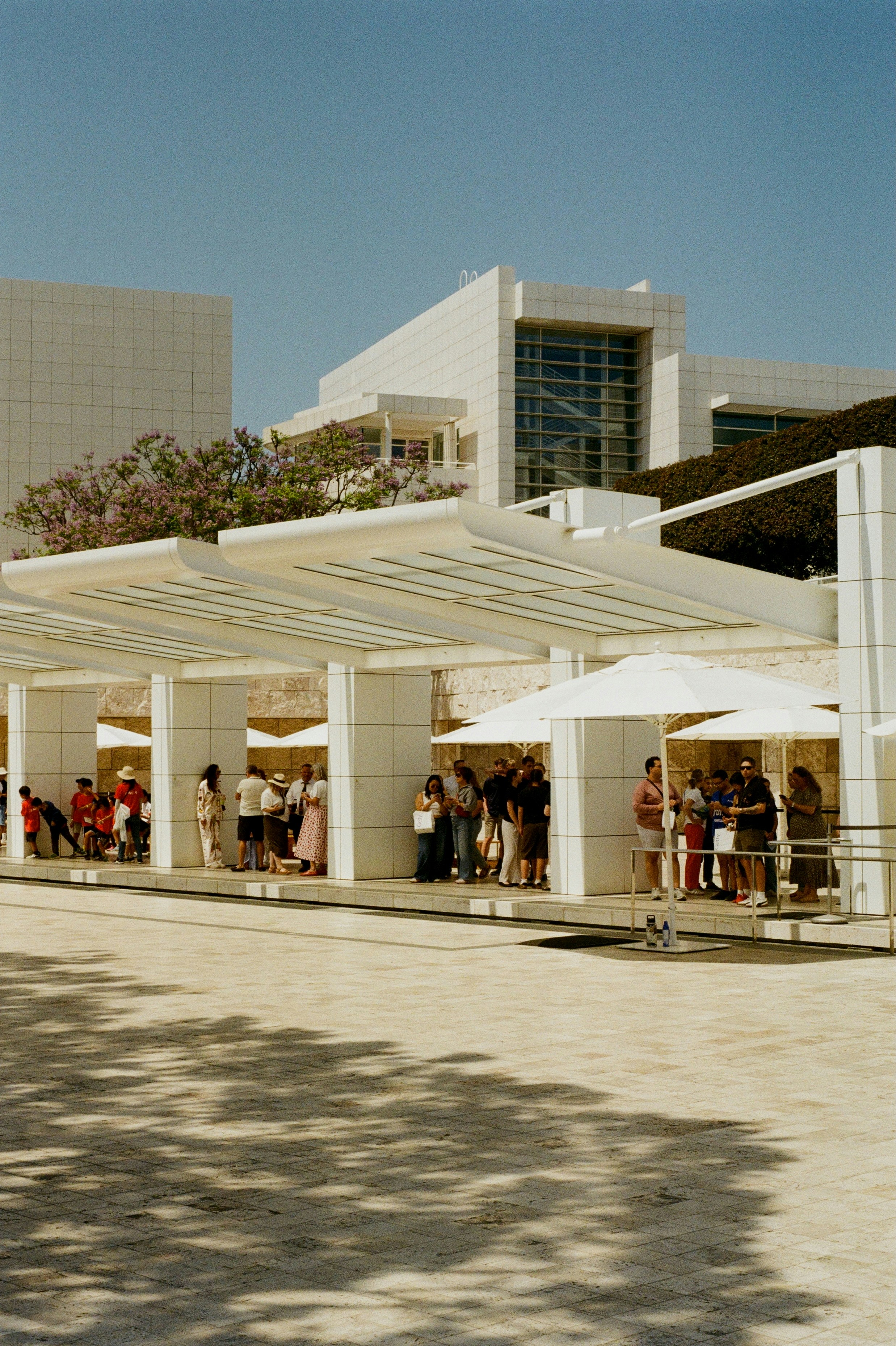 People queue outside a modern, white building.