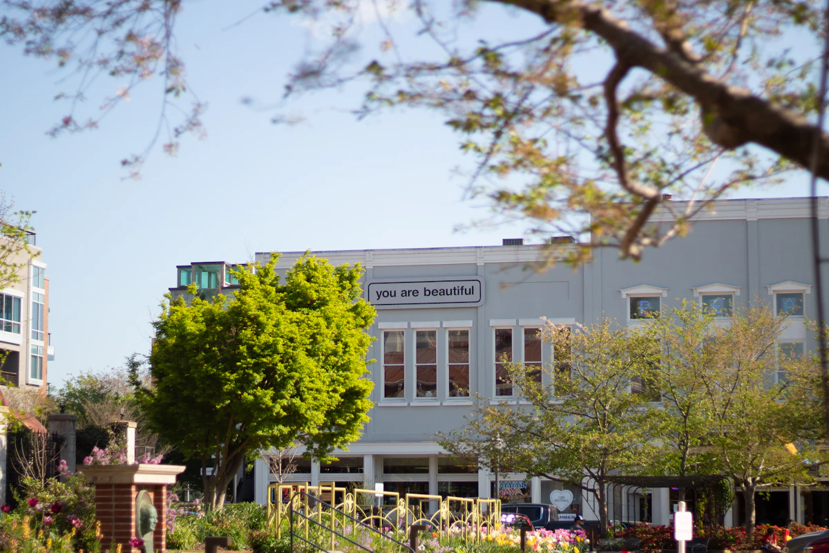 A pale building behind trees and flower beds in Fayetteville, Arkansas