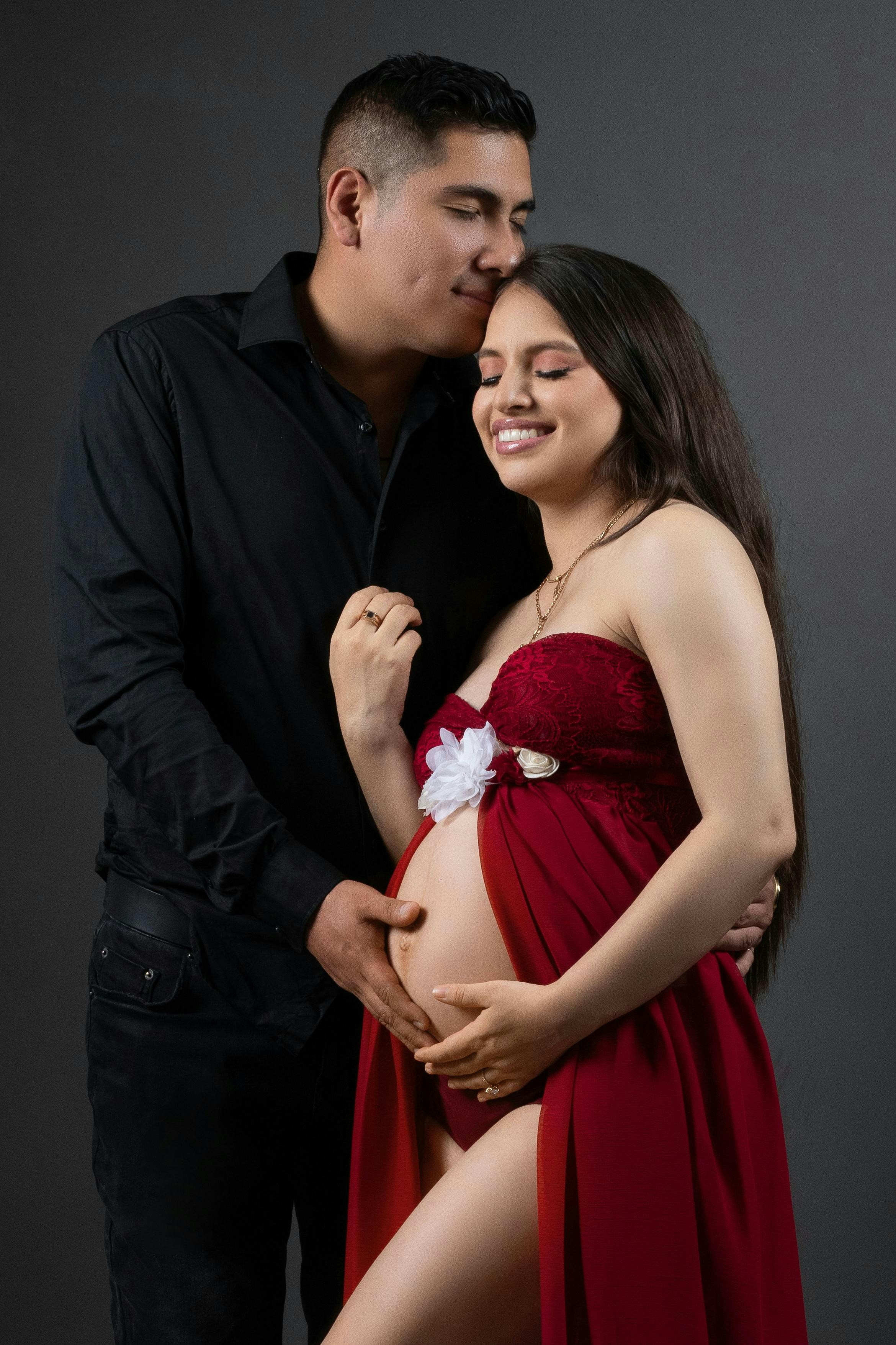 Loving couple embraces expectant mother.