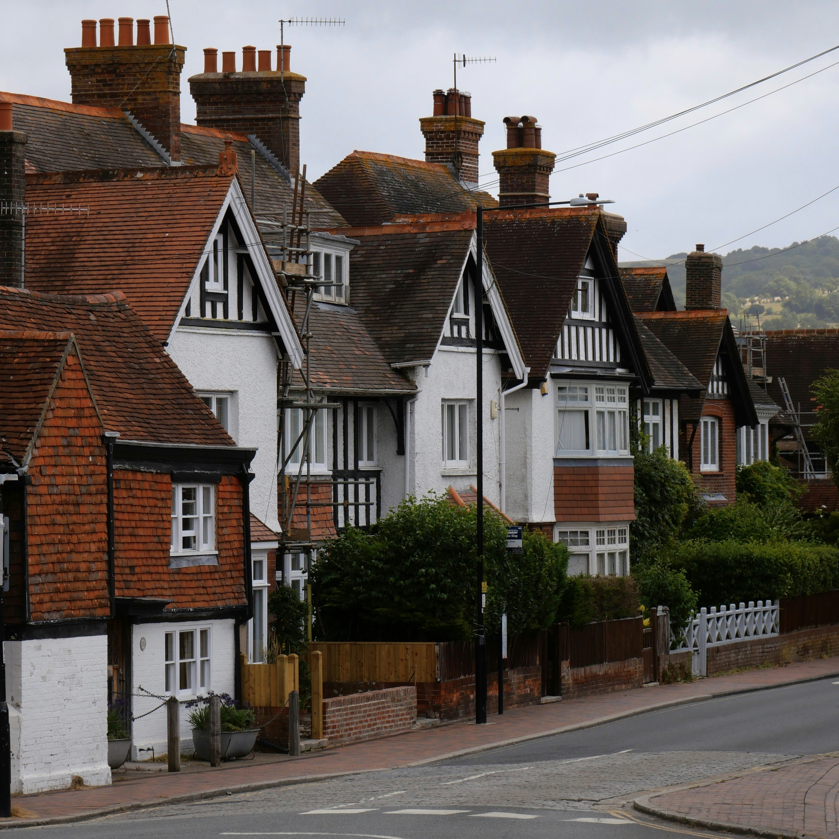 Houses with brick and dark-wood accents line a road.