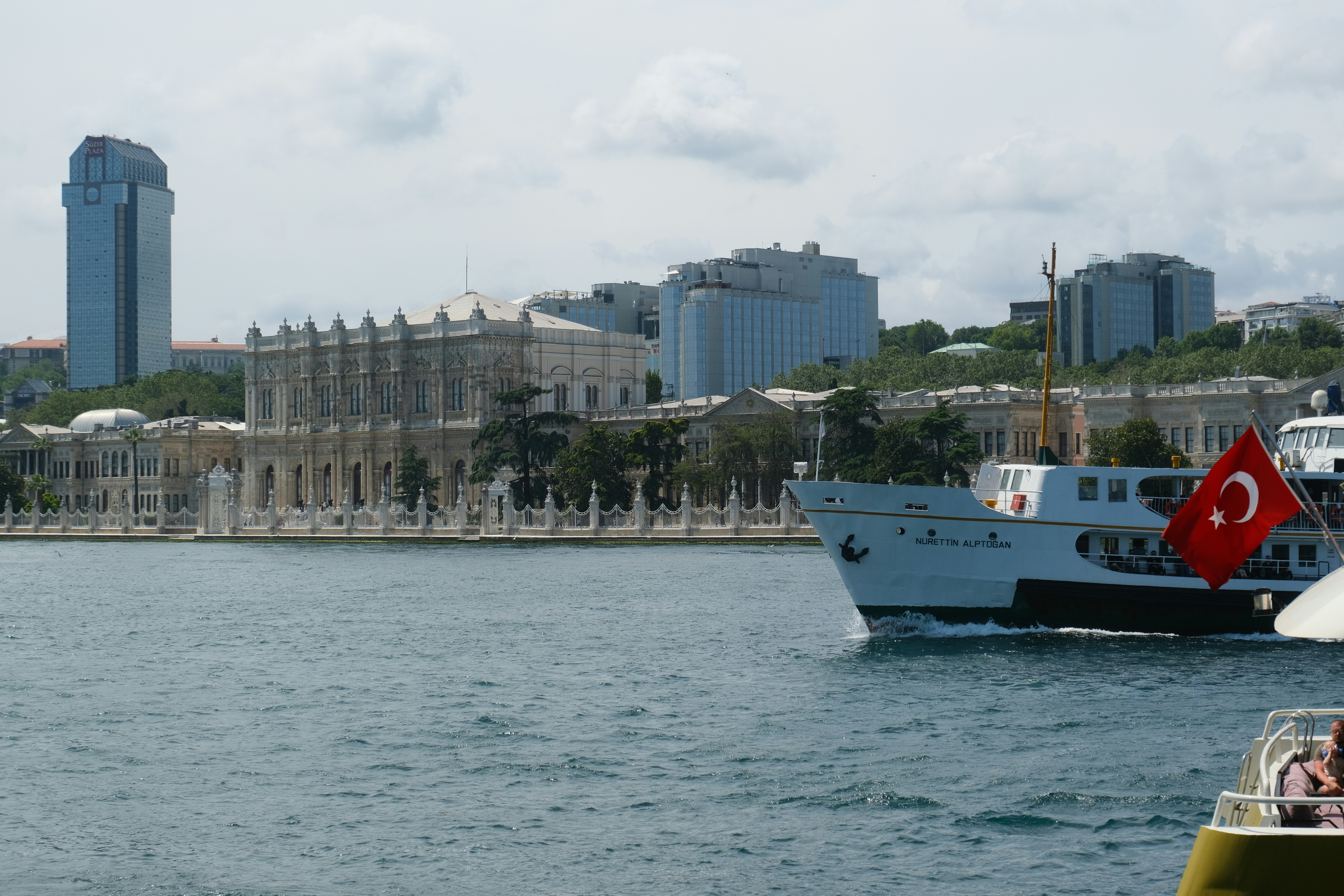 A turkish ship sails near a cityscape.