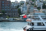 A boat sails near turkish buildings.