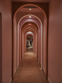 A pink hallway with archways and neon lighting