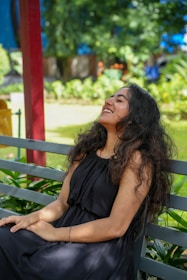 A smiling woman sits on a park bench.