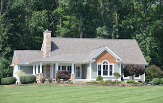 A beautiful house stands before a lush forest.