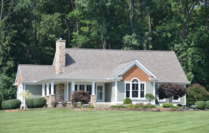 A beautiful house stands before a lush forest.