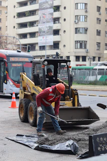 Construction workers are repairing the road with machinery.