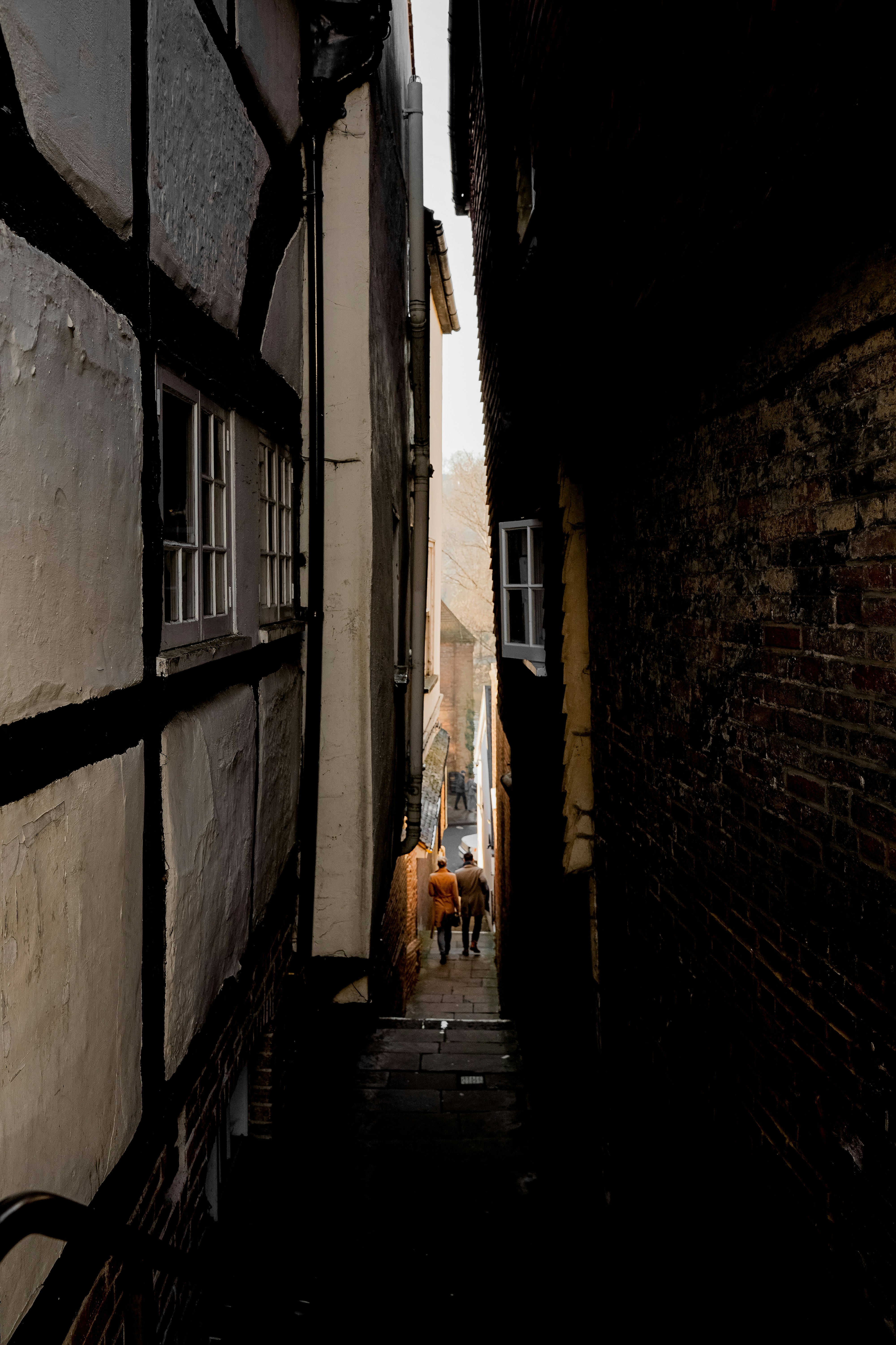 People walk through a narrow, shadowed alley.