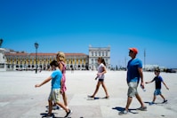 A family walks across a sunny, open square.