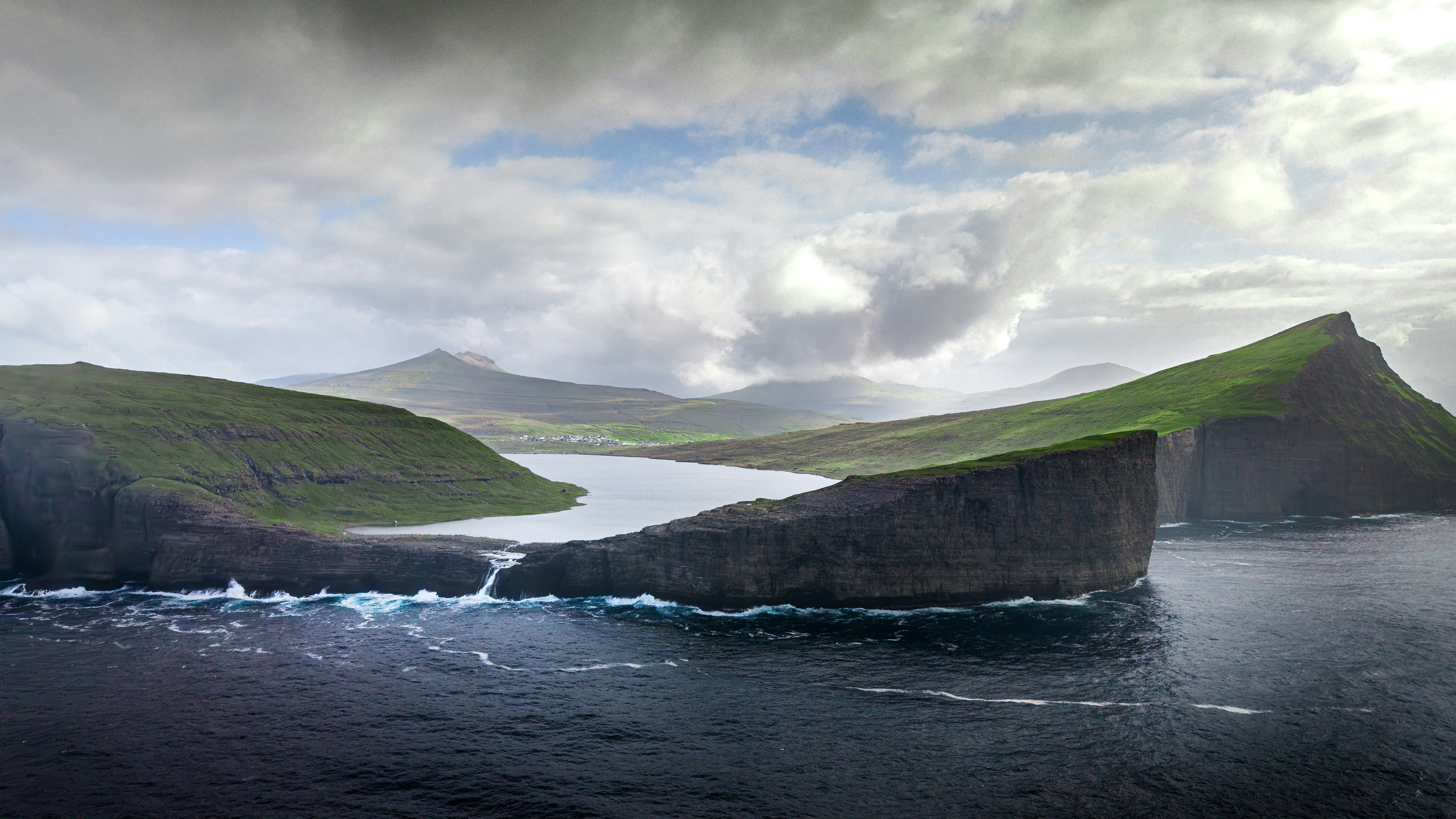 Dramatic cliffs border a lake and the ocean.