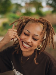 Smiling woman makes a call me gesture.