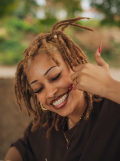 Smiling woman with dreadlocks gives a thumbs up.