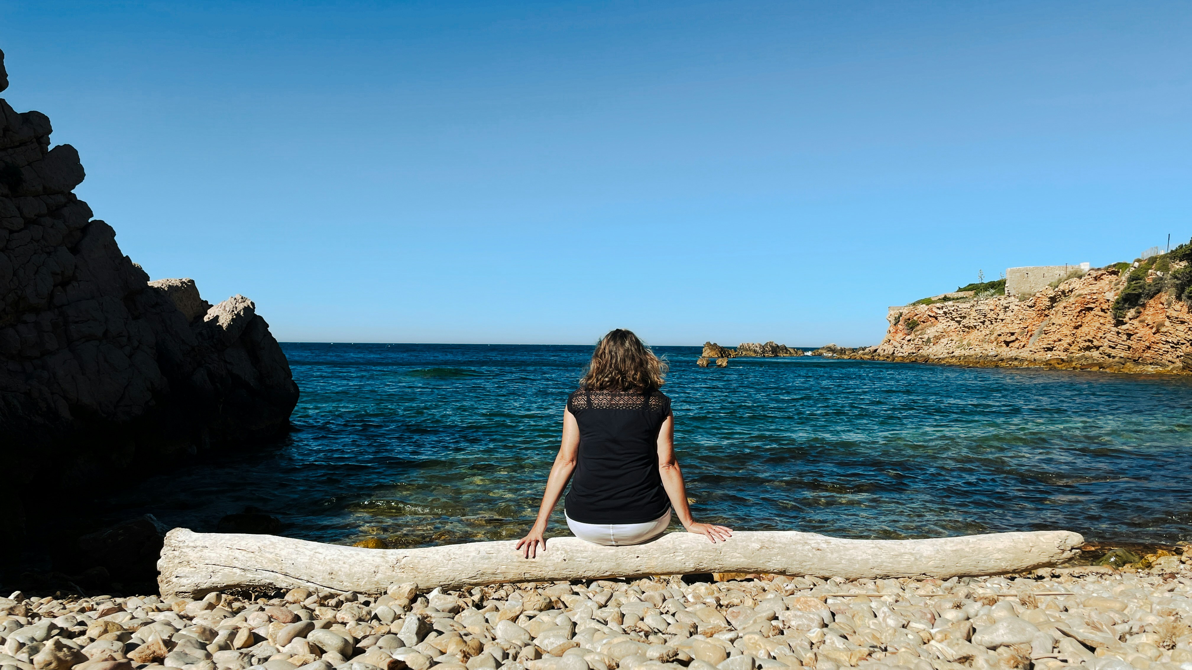 Woman relaxes on a log at the beautiful beach.