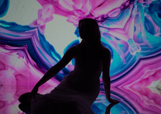 A silhouette poses before a colorful abstract background.