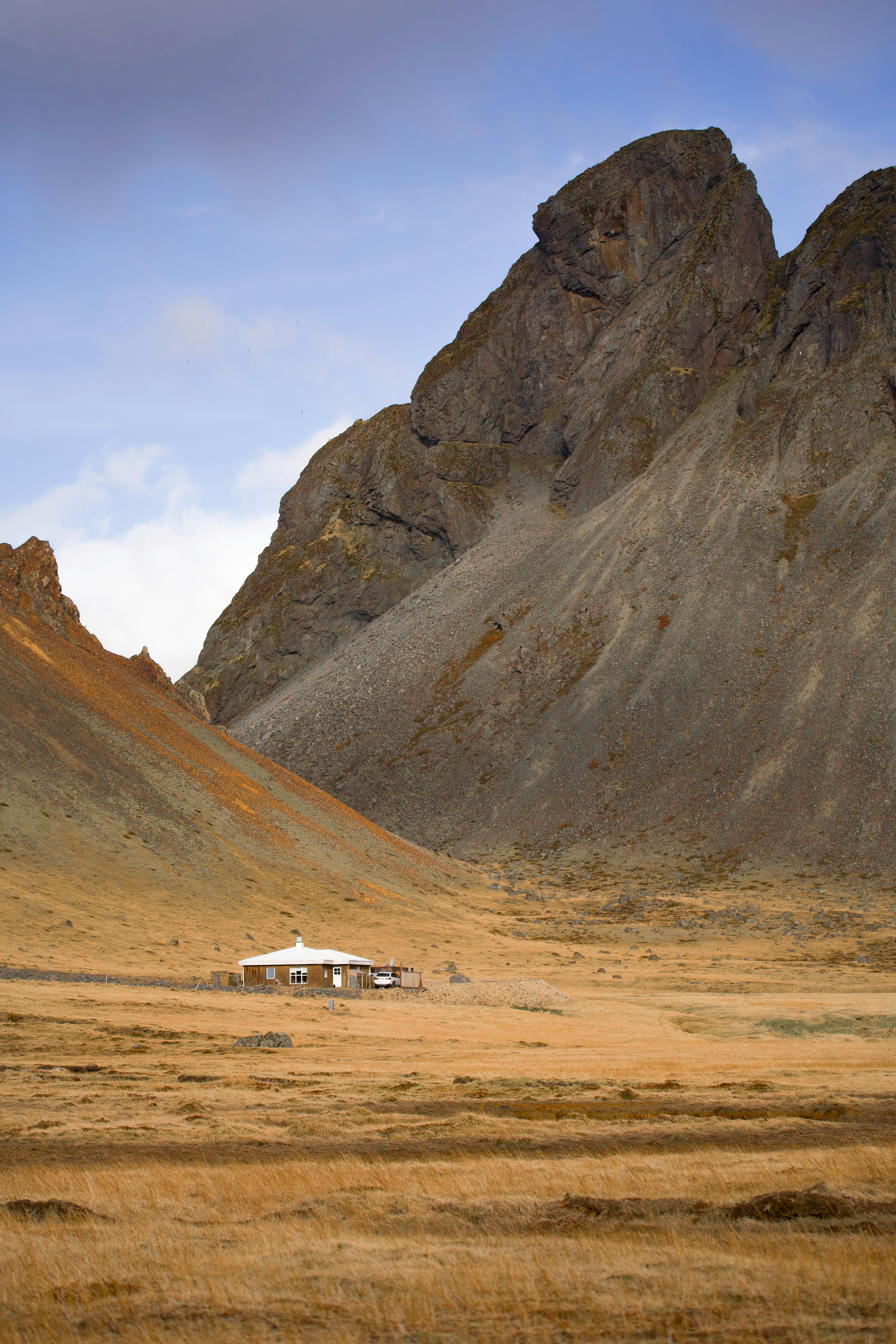 오두막은 산과 키 큰 풀밭 사이에 자리잡고 있습니다.