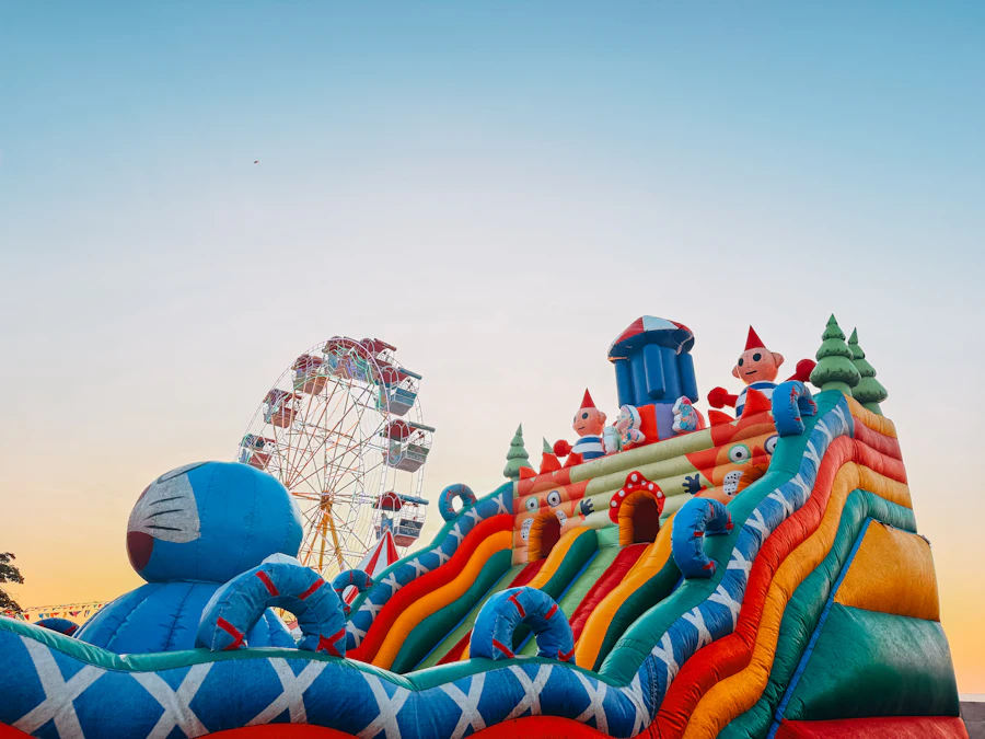 Obstacle courses, water slides and a bounce house set up on a grass field at a community event