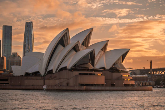 The sydney opera house shines in the sunset.
