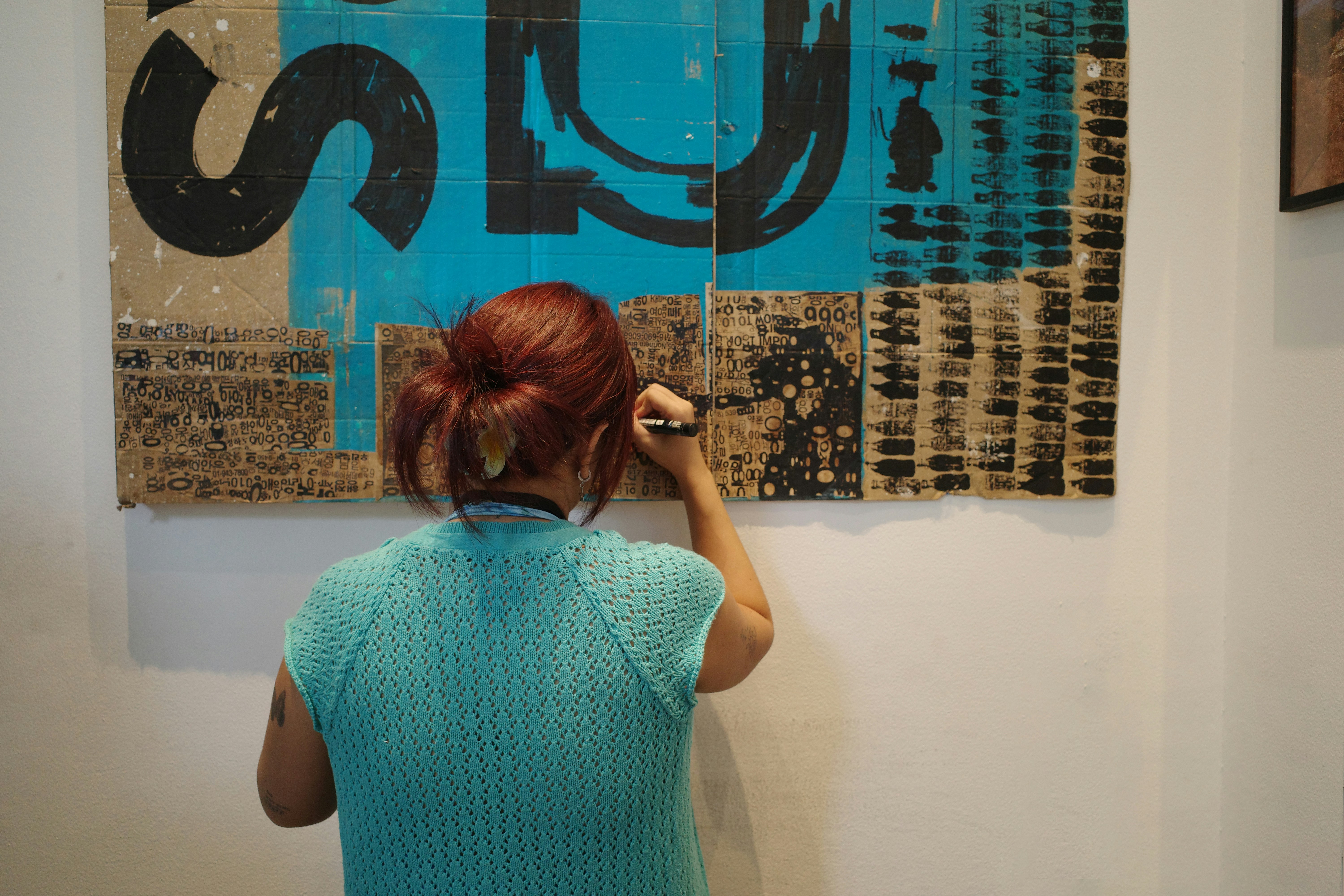 Artist paints on a canvas with blue and black hues.