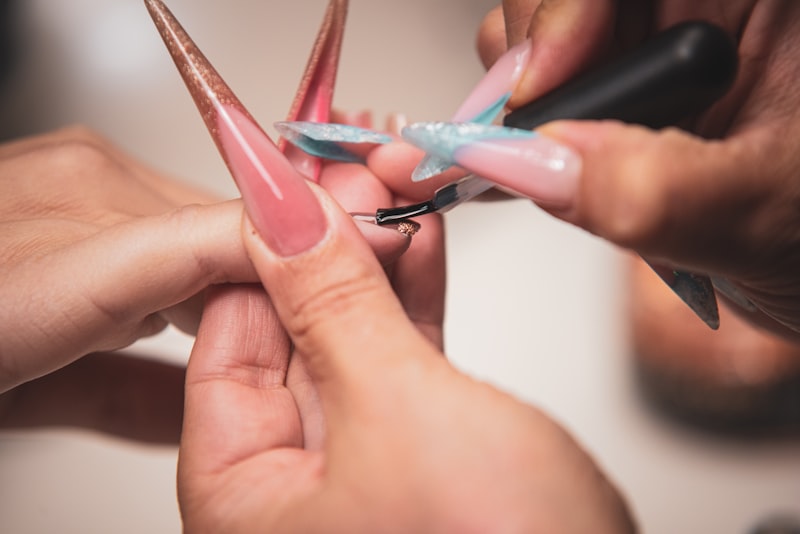 Manucure appliquant du vernis sur ongles artificiels
