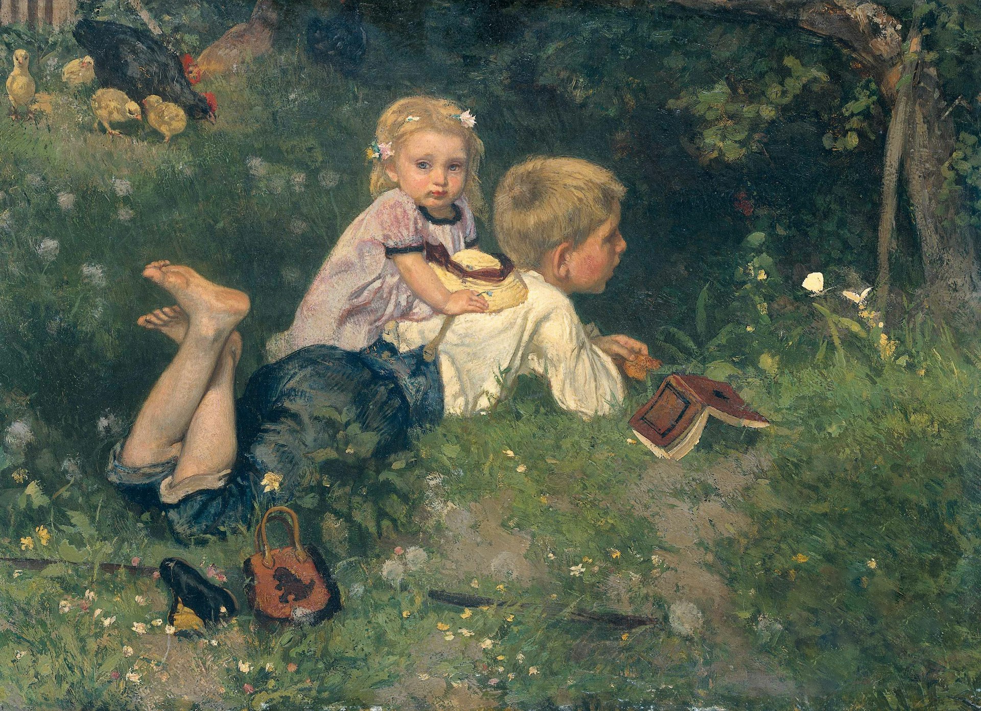 Two children lie in a grassy field with chickens.