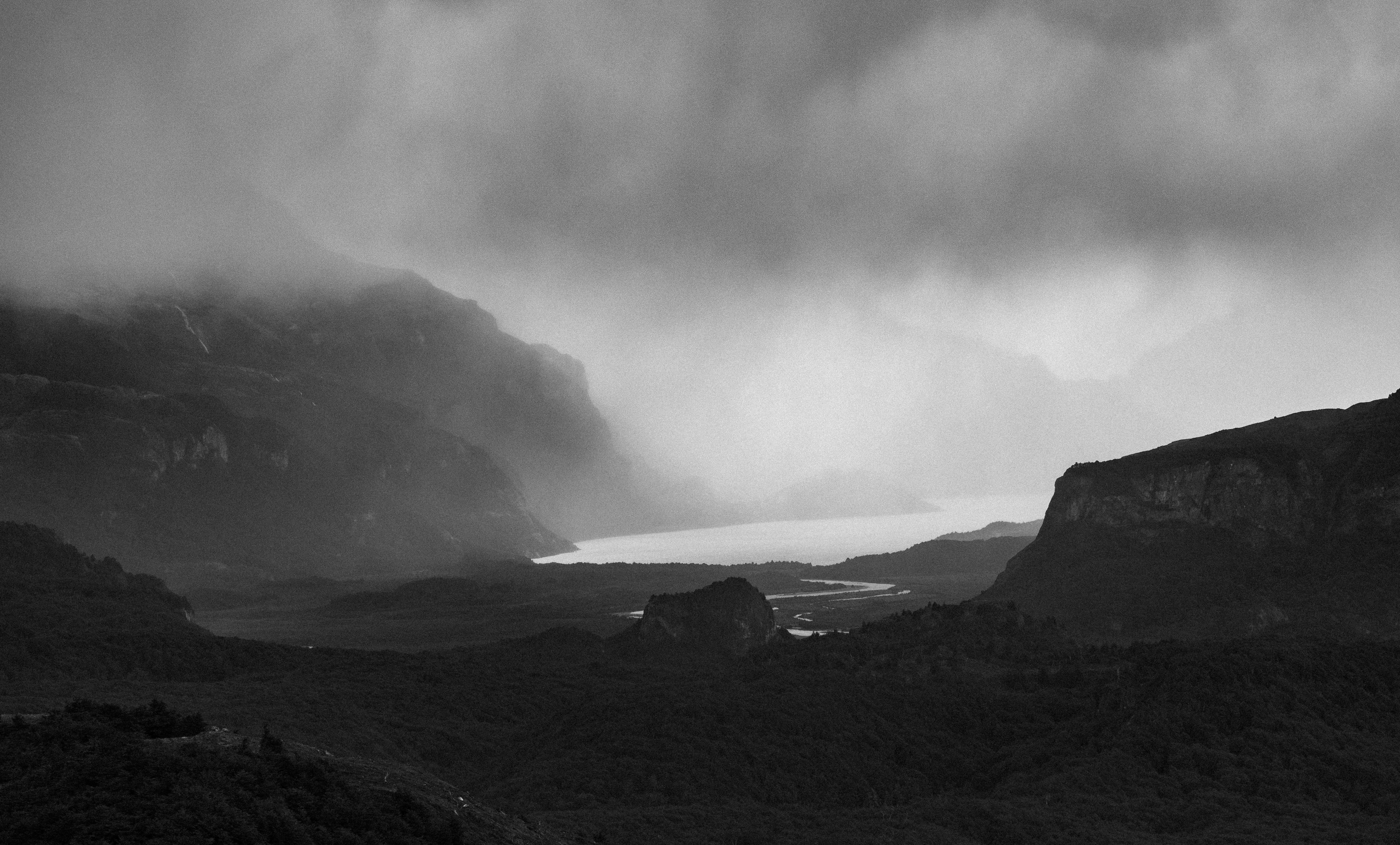Mountains and a lake are shrouded in a dark mist.