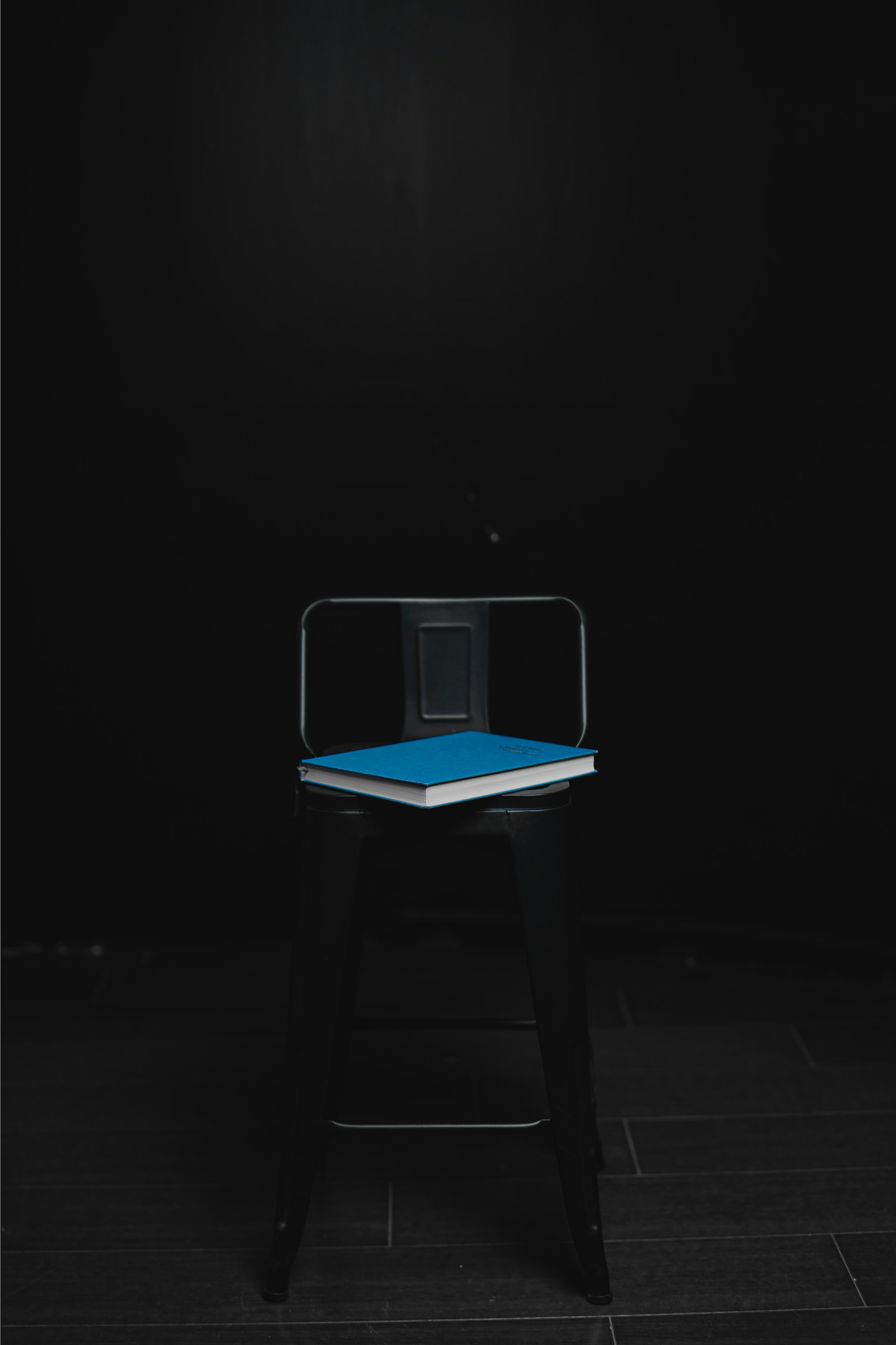 A blue book sits on a black stool.