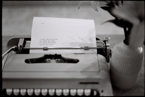 Typewriter with a typed poem next to a vase.
