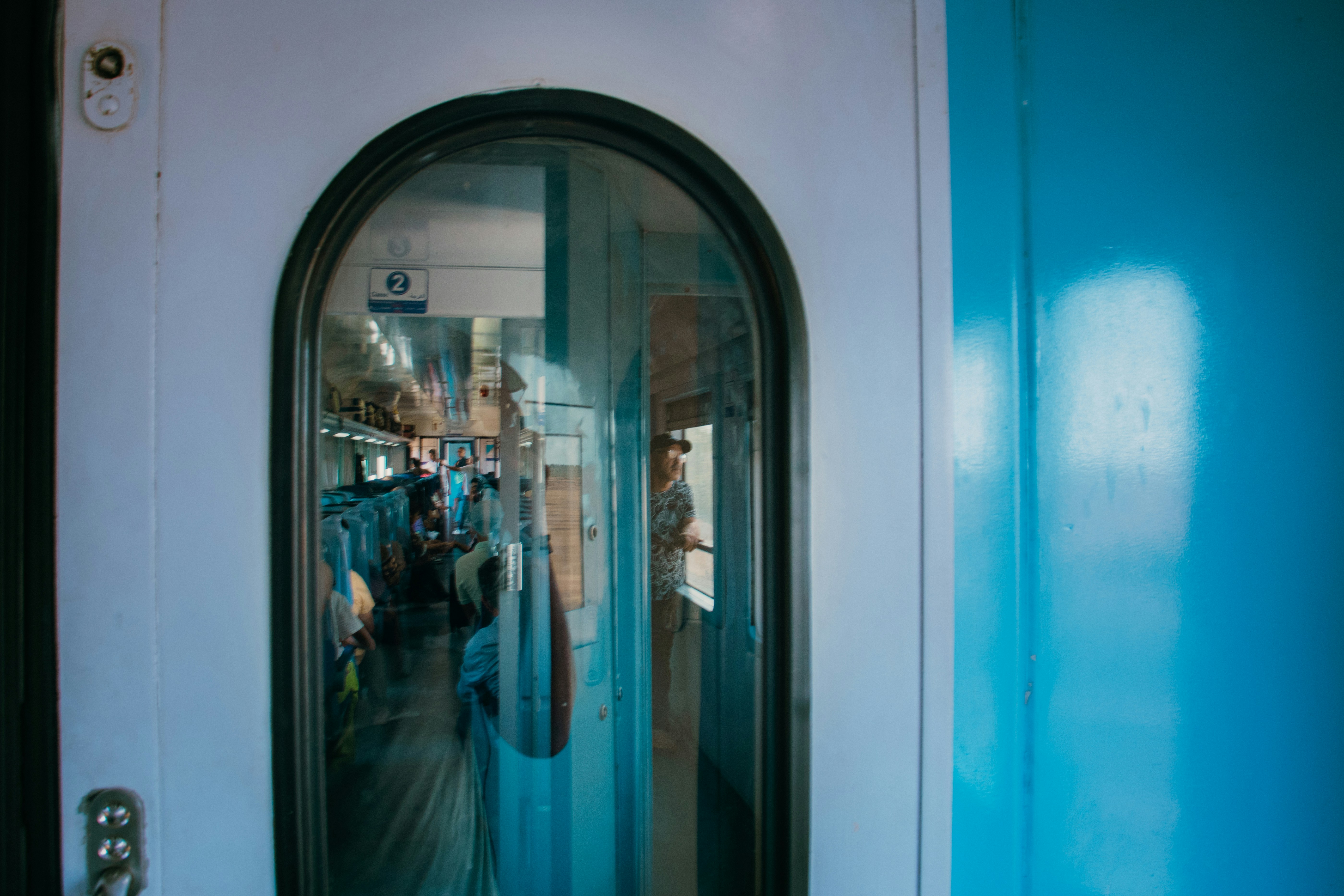 A train door reflects people and passengers.