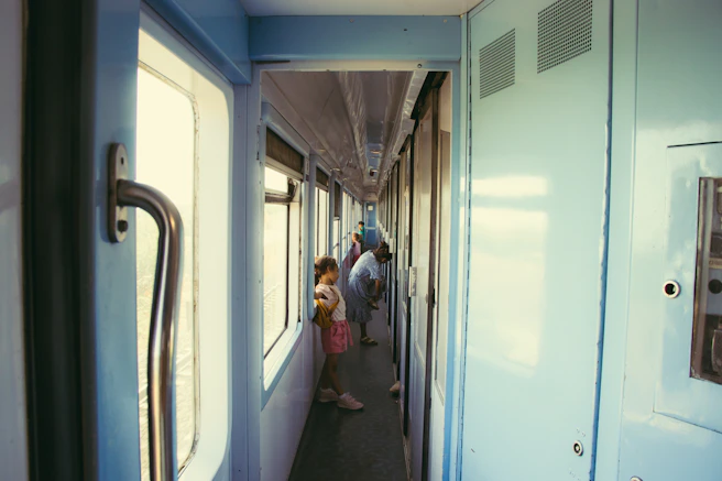 People stand in a long train corridor.