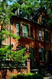 A brick house is surrounded by green trees.