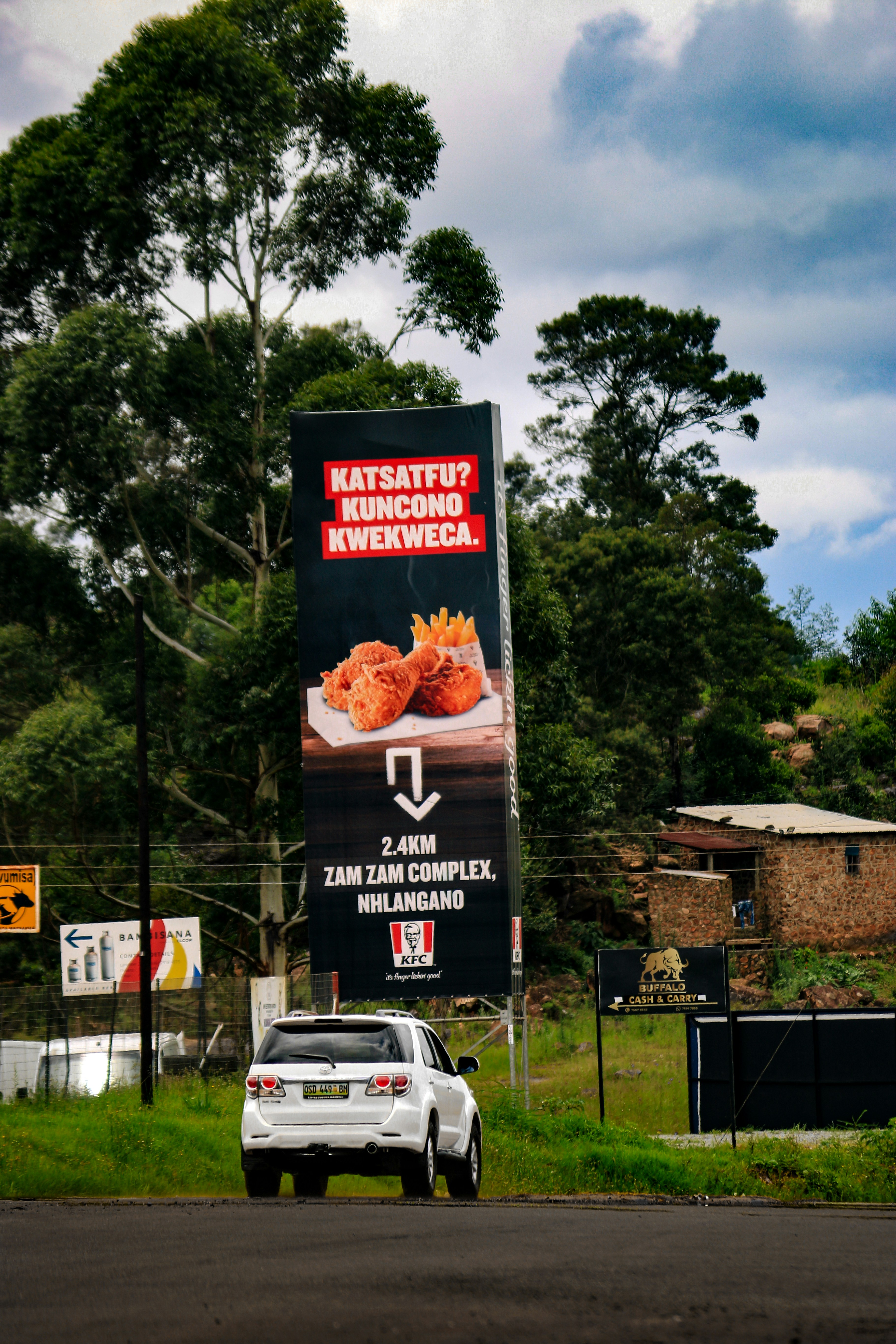 A kfc billboard points the way to a restaurant.