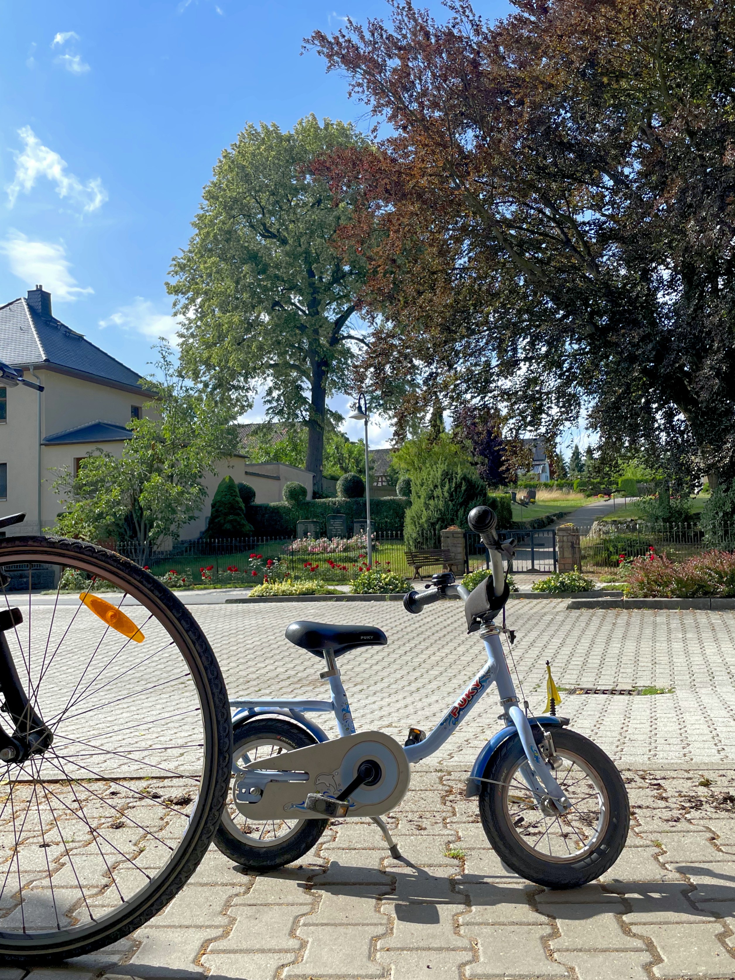 A child's bike sits near a parked adult bike.
