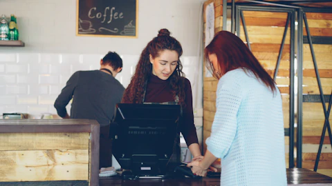 A customer is paying a clerk at a cafe counter.