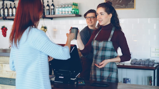 A barista handing coffee to a customer at the counter.