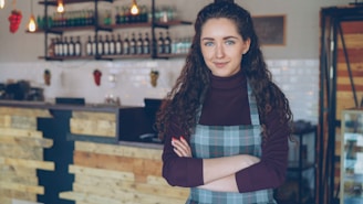 A smiling woman stands in her coffee shop.