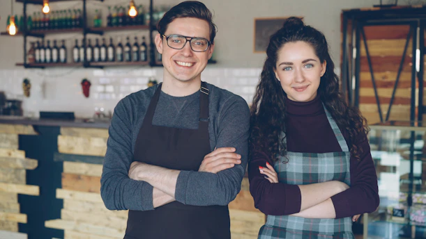 Two cafe owners proudly stand together.