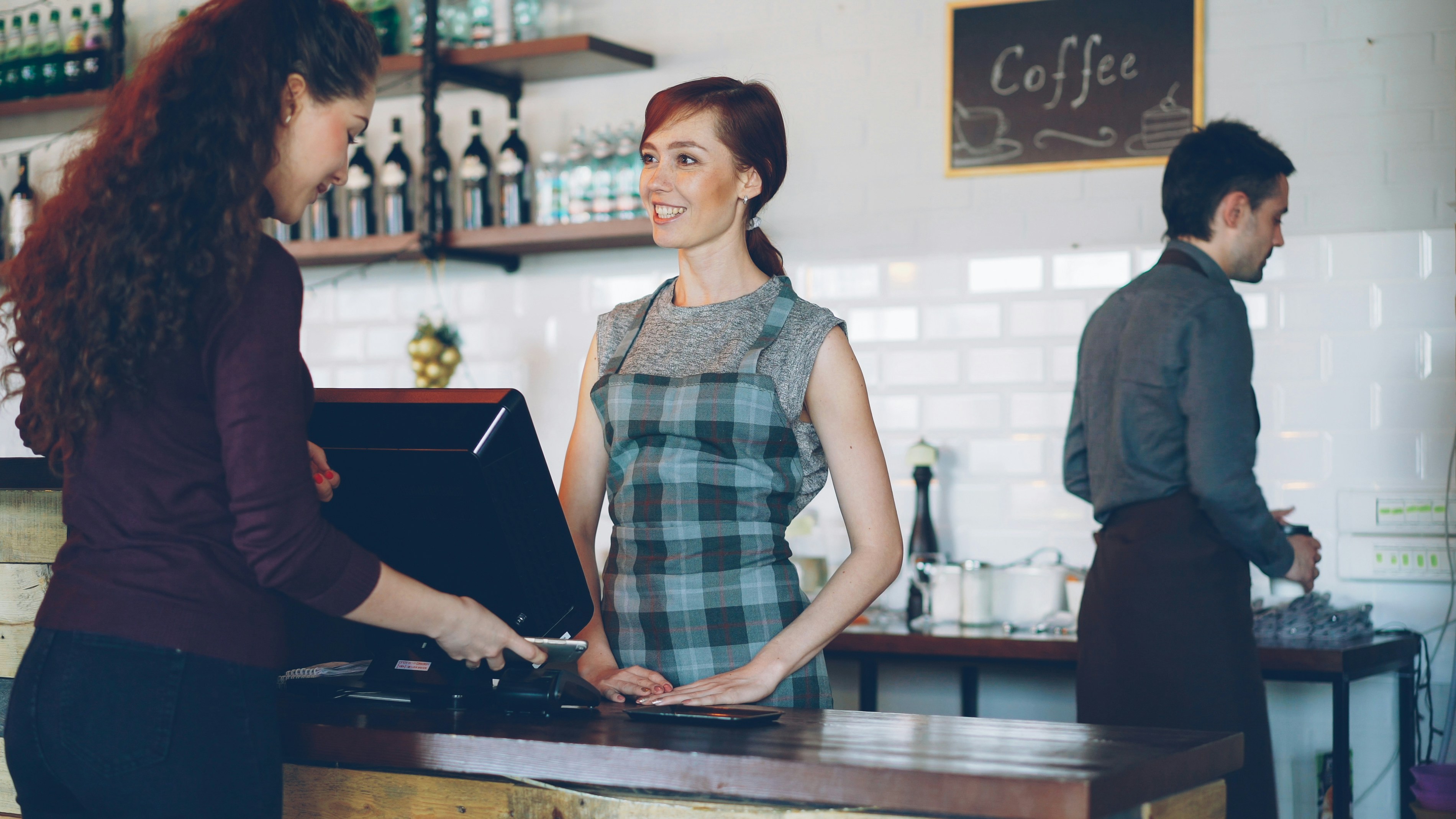 How to Build a Customer Loyalty Program That Actually Works for Small Businesses – A customer pays at a coffee shop counter.