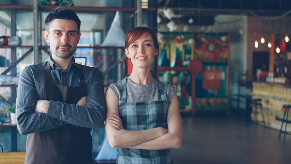 Cafe owners in aprons standing together