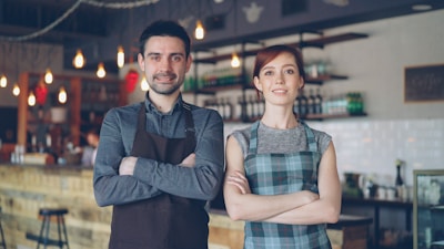 Two people pose confidently in a coffee shop.
