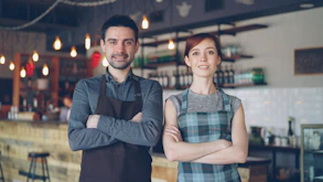 Two people pose confidently in a coffee shop.