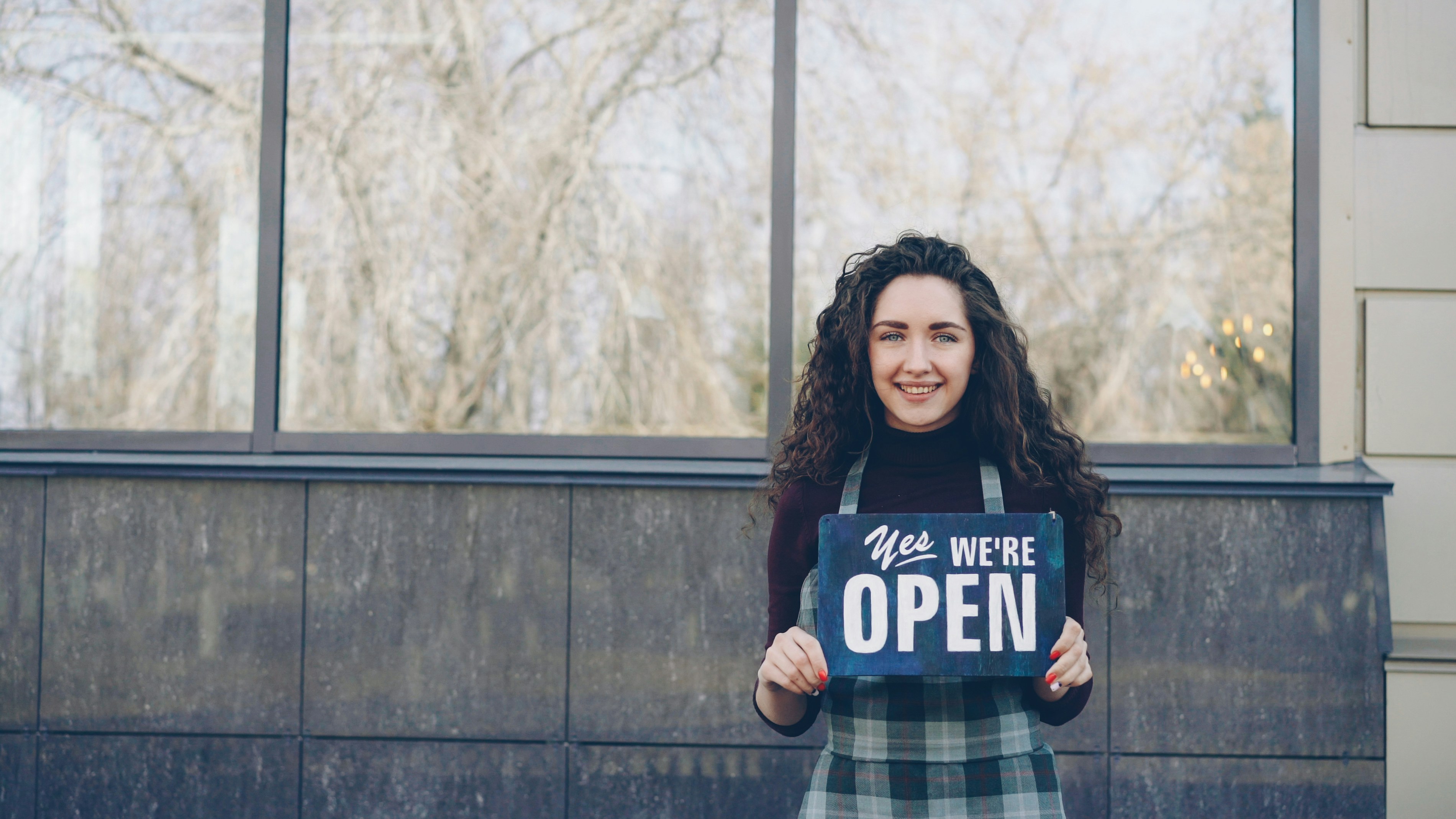 Cheerful waitress holding open sign