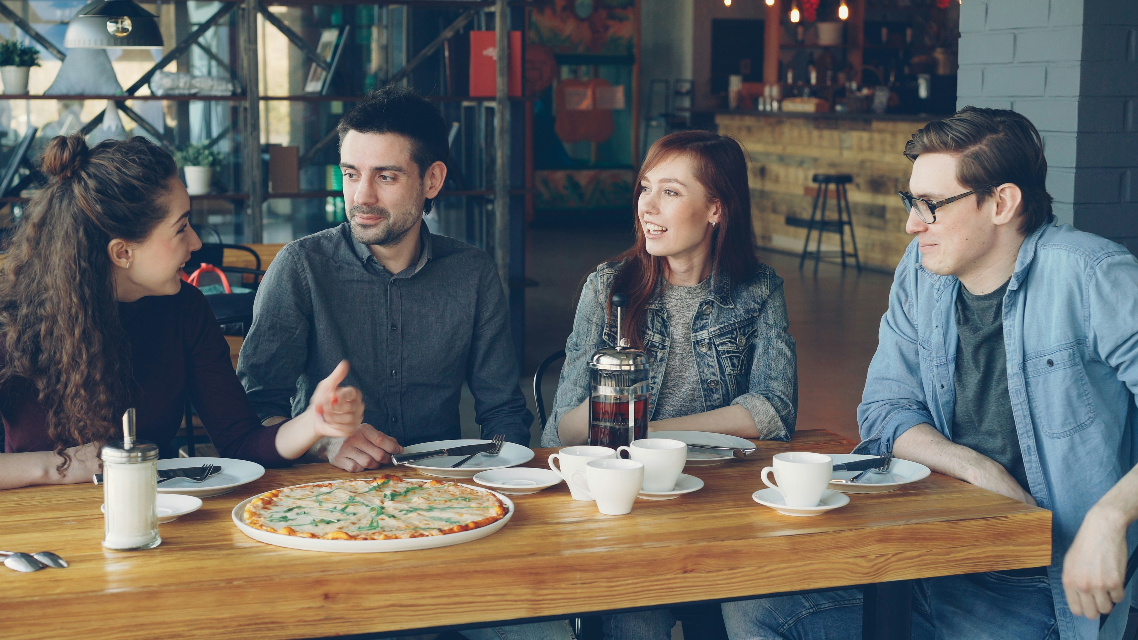 A family happily enjoying a meal together, with a delicious pizza as the centerpiece, in a bright and casual restaurant setting - best pizza Uptown Chicago