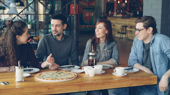 Friends enjoy pizza and conversation in a restaurant.