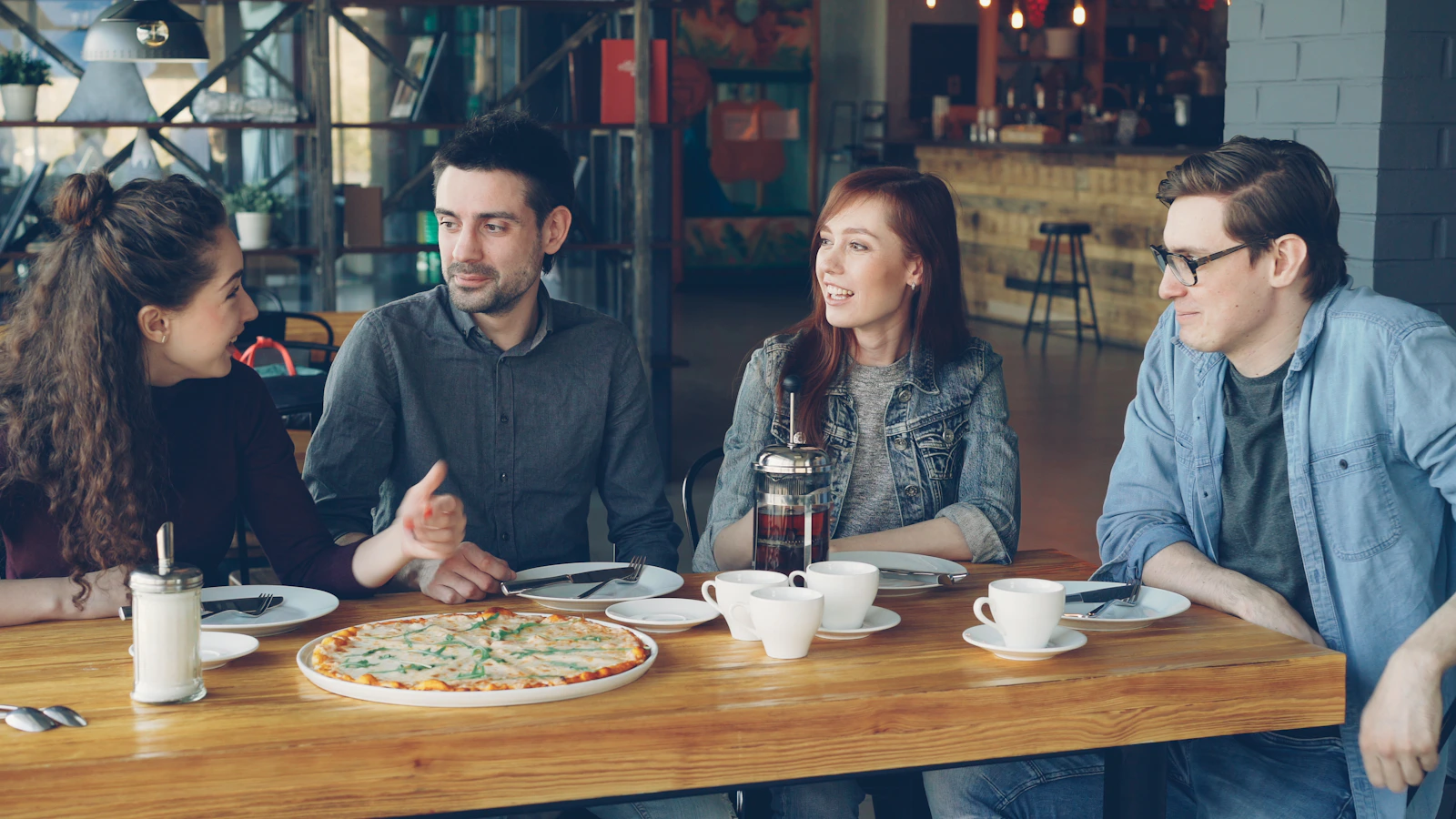 Friends talking over coffee and pizza in a café