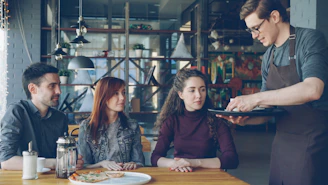 A waiter serves food to a couple in a restaurant.