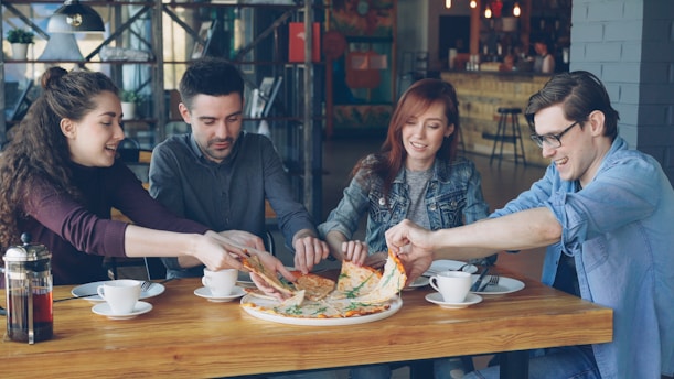 Friends are sharing a pizza at a restaurant.