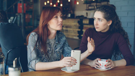 Two women converse at a cafe
