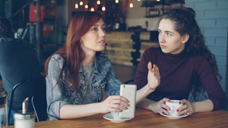 Two women converse at a cafe.