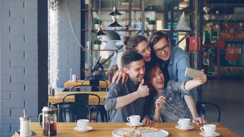 Friends are taking a selfie in a cafe.