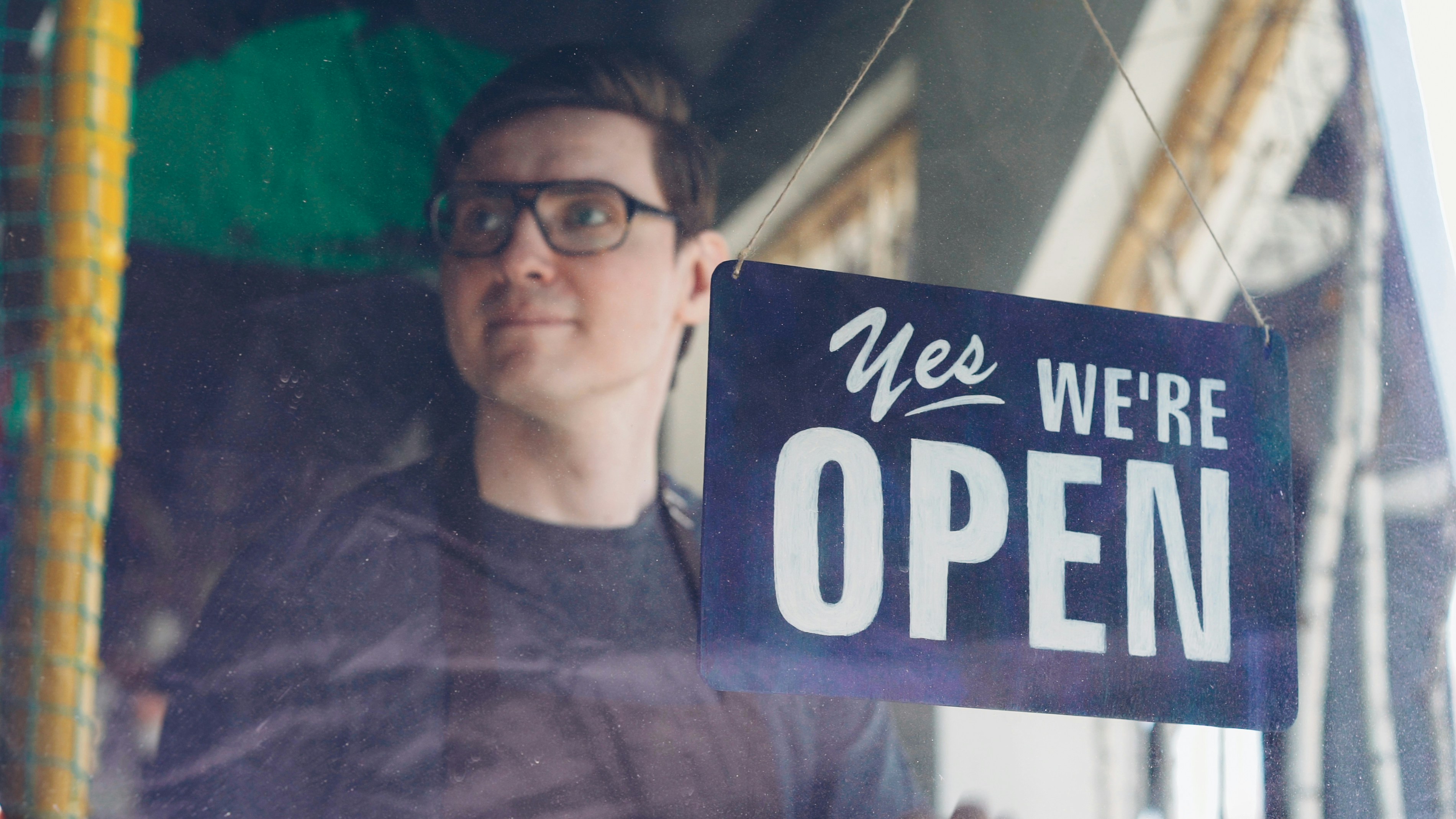 A man proudly displays an "open" sign.